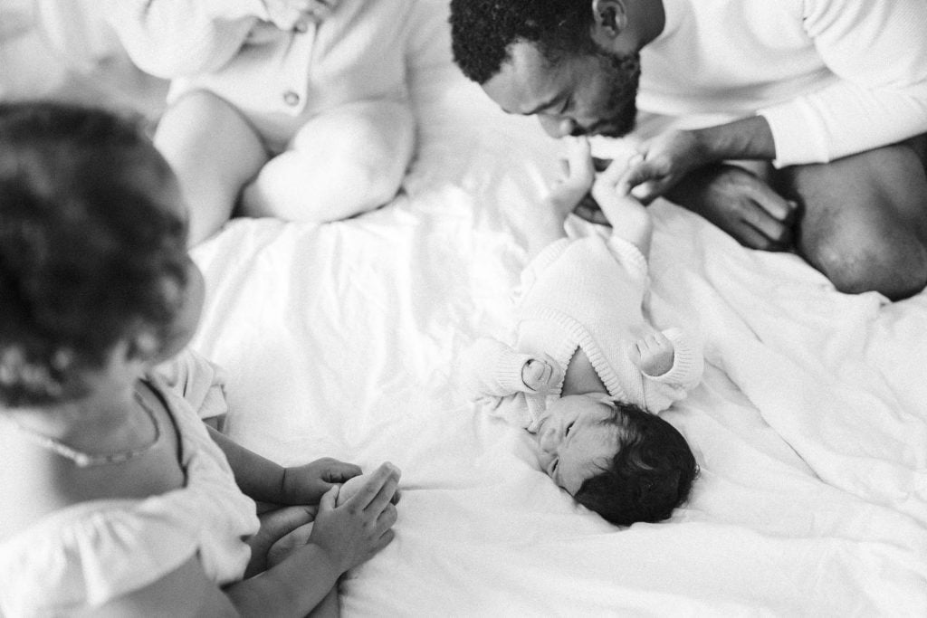 Dad kisses newborn baby's foot on their bed at home during montreal photoshoot