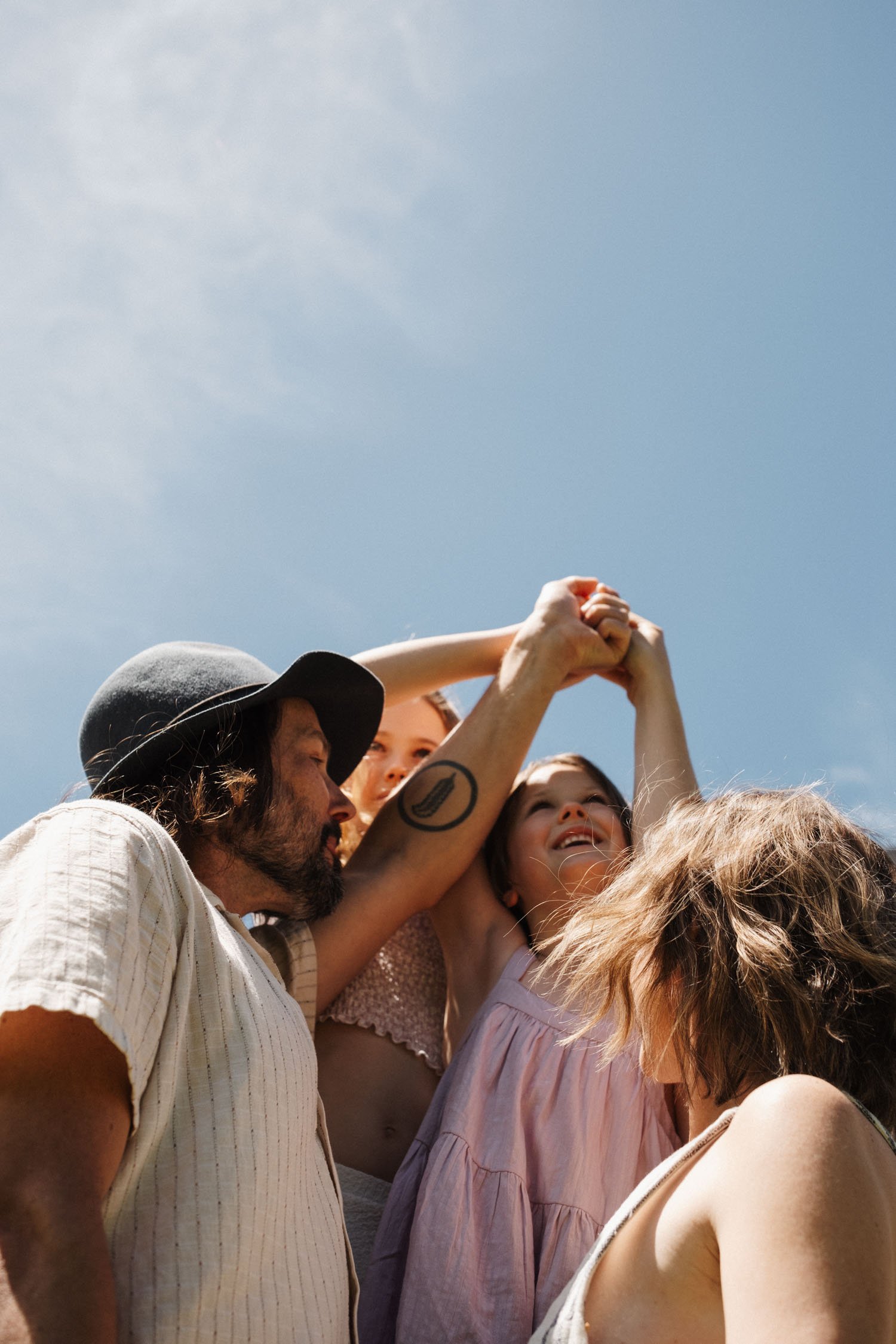 Family of 4 hold their hands up in the sky during their montreal family photo shoot