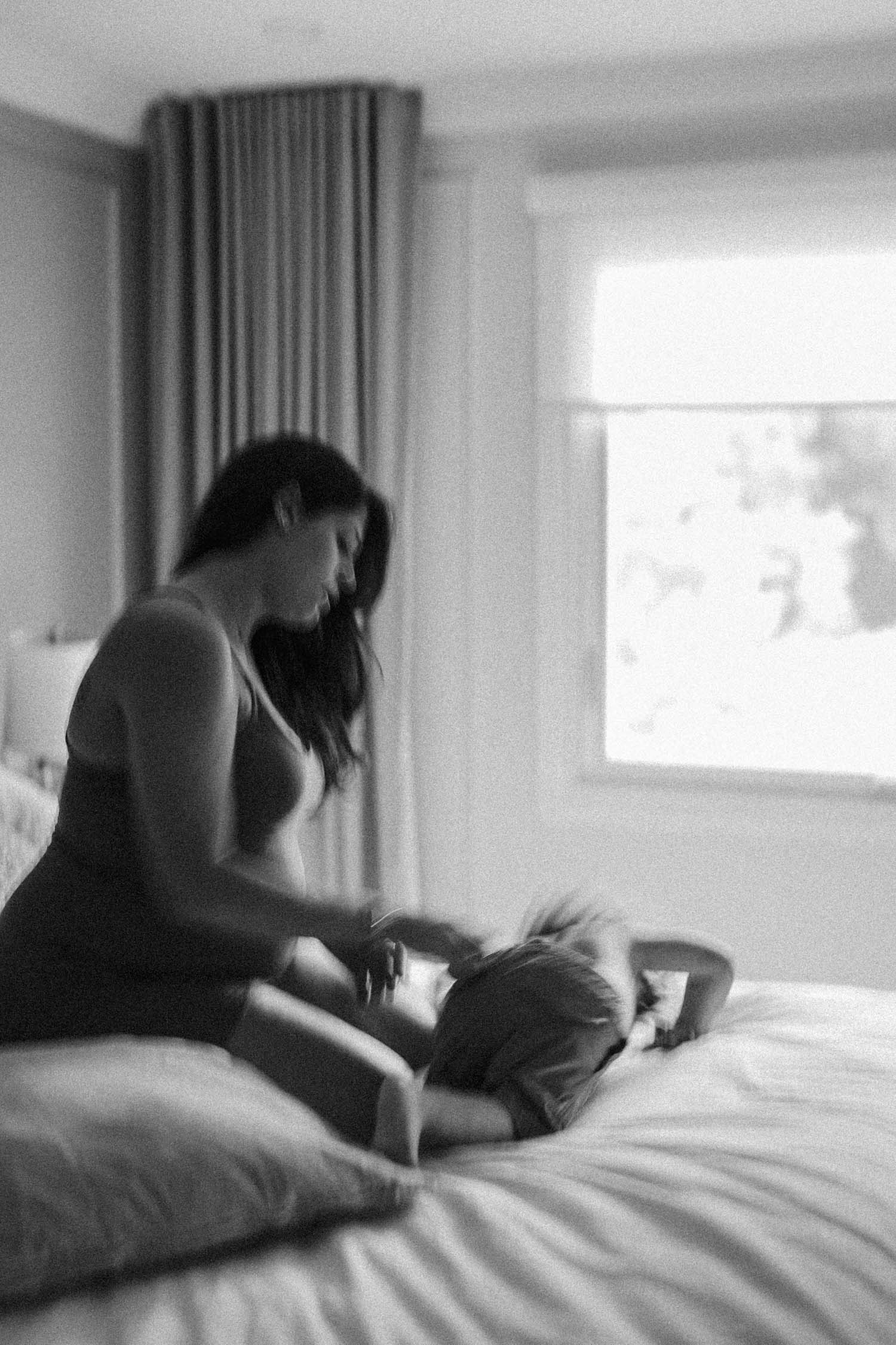 Blurry, slow shutter image of pregnant mom and toddler son during their in-home maternity photo session in Montreal